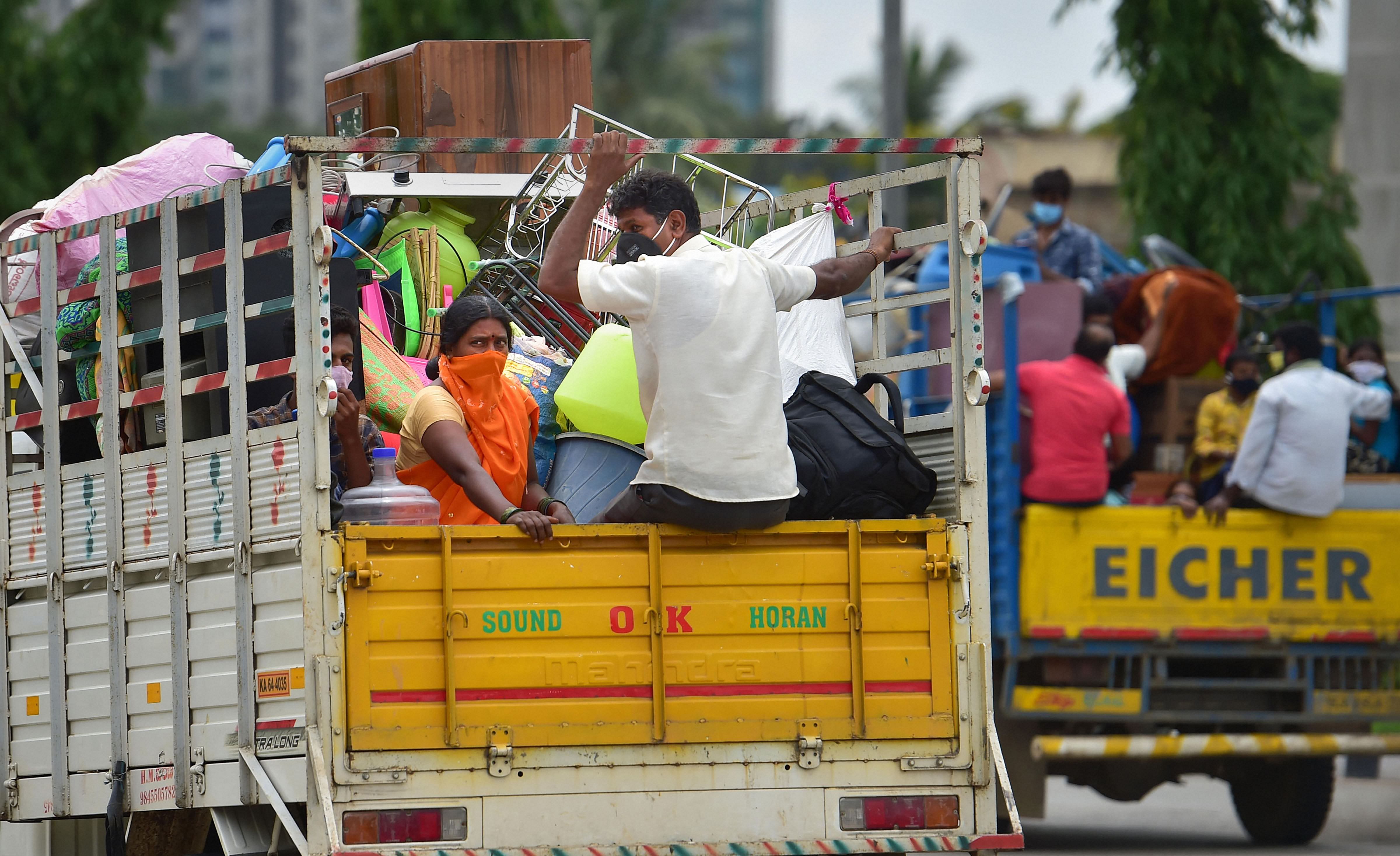 Migrants with their belongings travel in a tempo as they leave the city after authorities announced one week lockdown due to surge in Covid-19 cases, in Bengaluru. Credits: PTI Photo