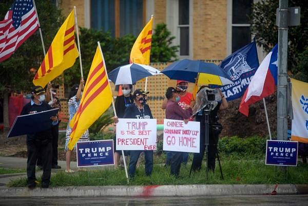Protesters hold up signs and flags outside of the Chinese consulate in Houston. Credit: AFP