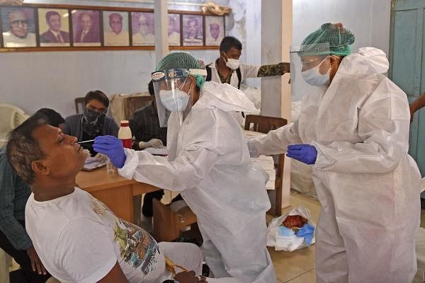 Health workers wearing Personal Protective Equipment (PPE) suits take a swab sample from a man during a medical screening for coronavirus, in Ahmedabad. Credit: AFP