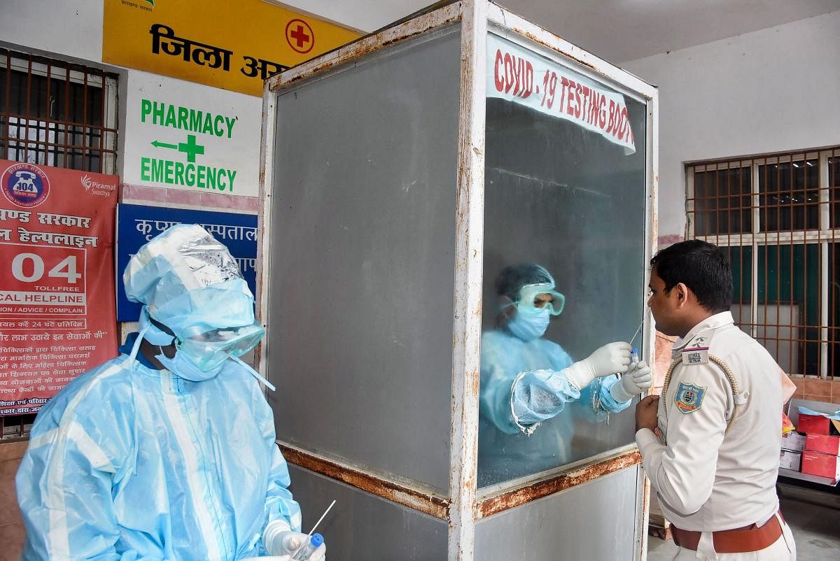 A health worker collects sample from a policeman for Covid-19 test at the District Hospital in Ranchi. Credit:PTI