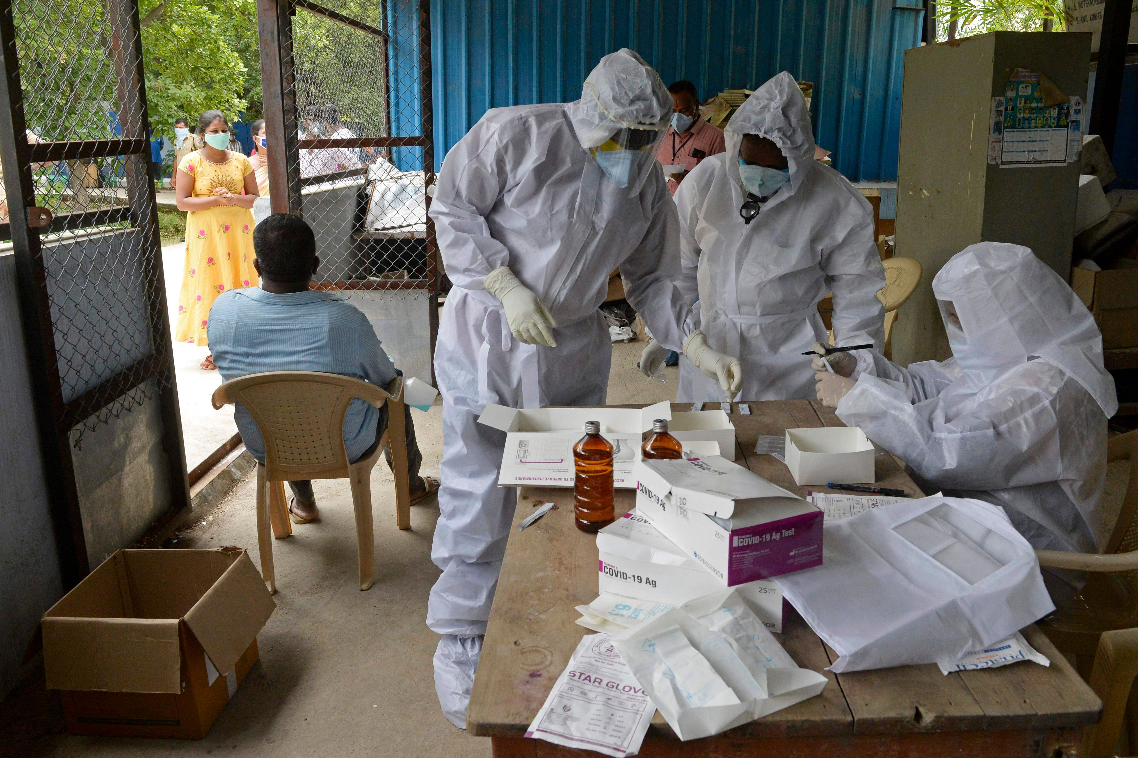 Health workers wearing Personal Protective Equipment (PPE) gear prepare to collect swab samples of residents at a free testing centre for the COVID-19 coronavirus, at Ranga Reddy district on the outskirts of Hyderabad. Credits: AFP Photo