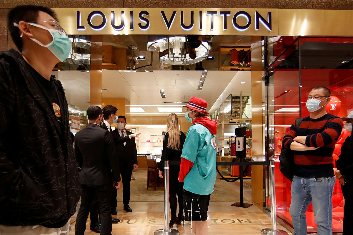 Customers, wearing protective face masks, stand in front of a Louis Vuitton shop inside the department store Le Printemps Haussmann in Paris, France. Credit: REUTERS