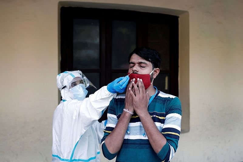A medical health worker in a Personal Protective Equipment (PPE) collects a sample from a person using a swab, at a school which was turned into a centre to conduct tests for the coronavirus. Credits: Reuters Photo