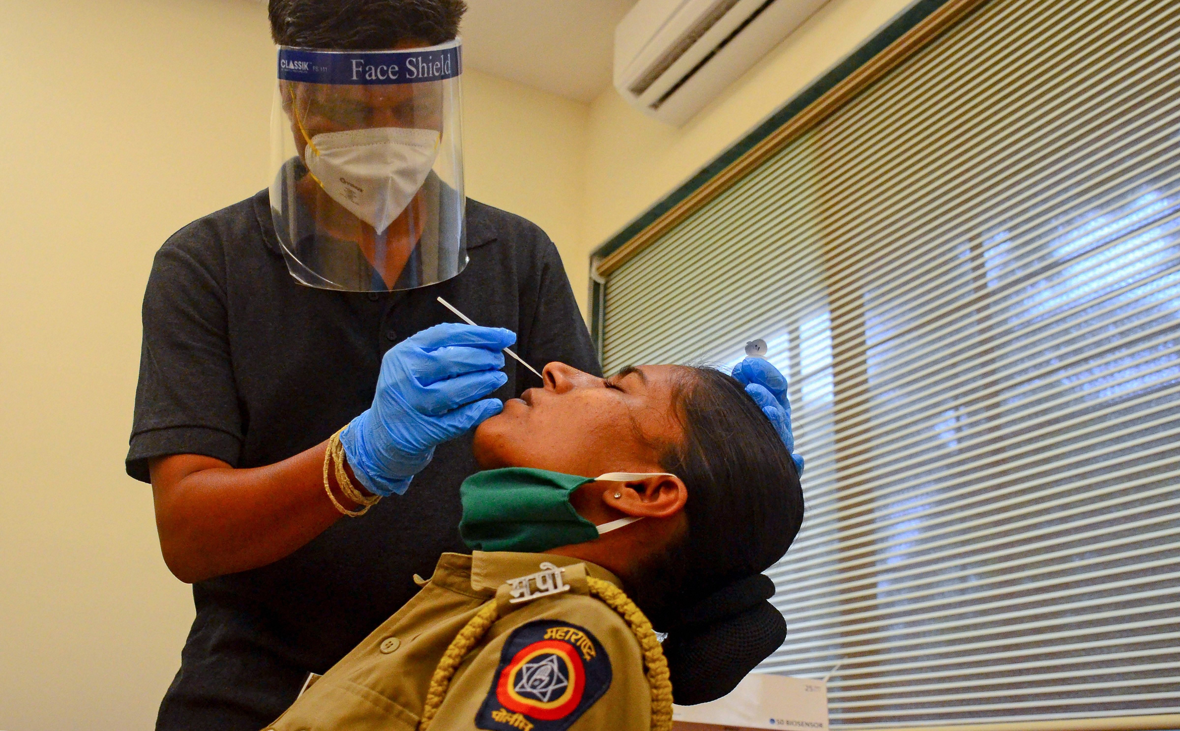 Navi Mumbai Municipal Corporation (NMMC) doctor collects swab sample of police personnel for Covid-19 Rapid Antigen Test. Credits: PTI Photo