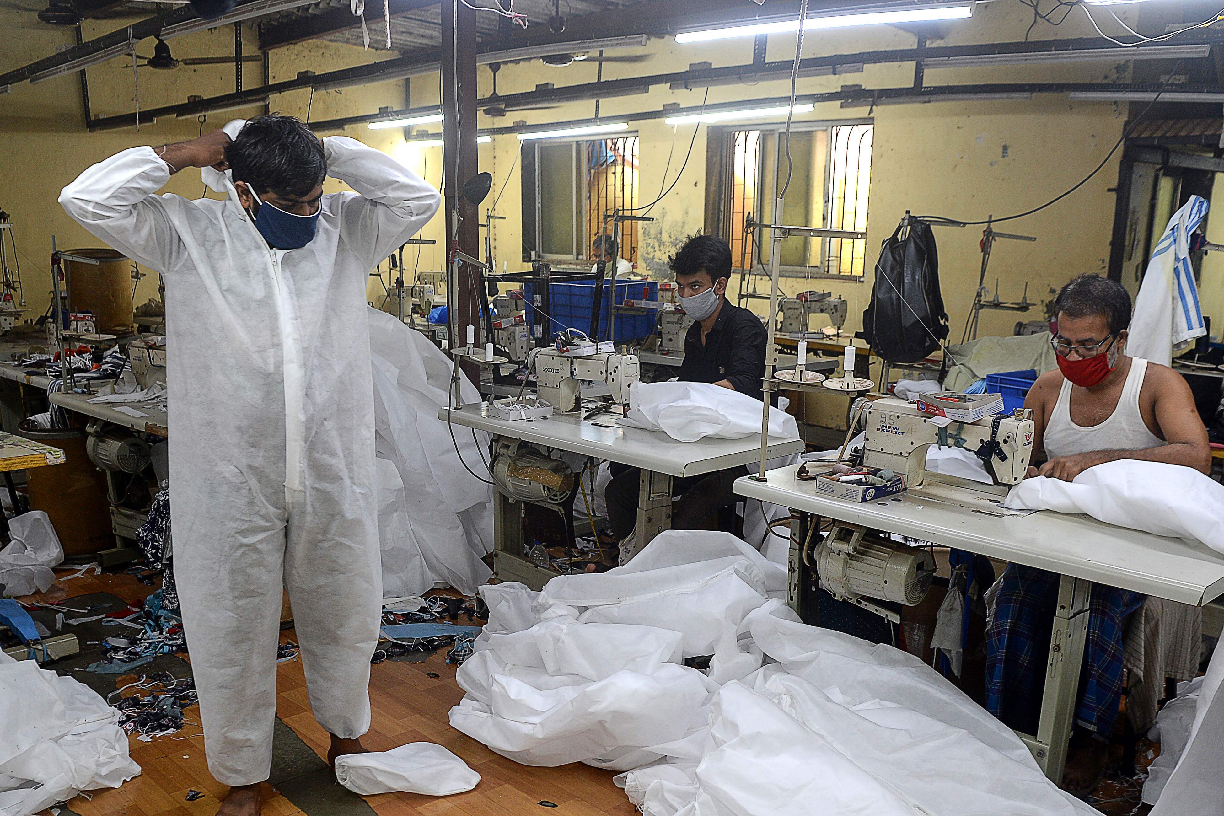 A supervisor inspects one of the finished Personal Protective Equipment (PPE) products at a garment manufacturing unit. Credit: AFP Photo