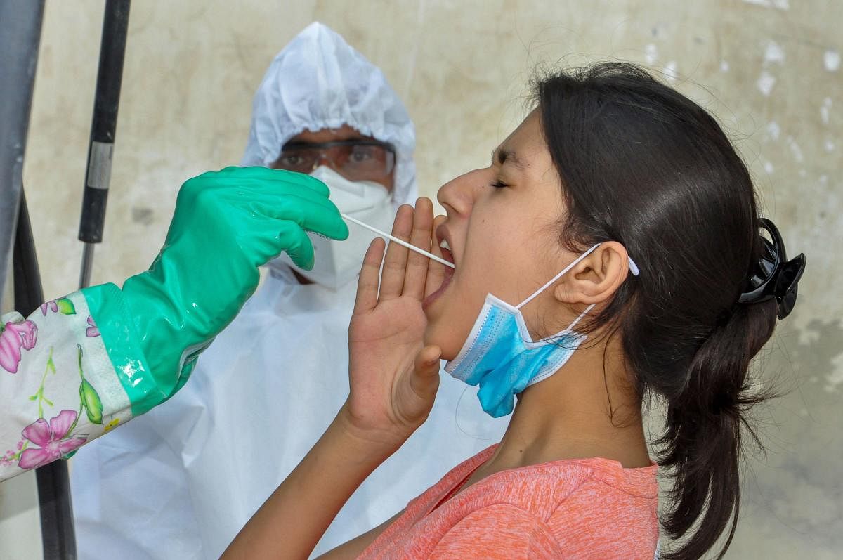 A medic collects a swab sample from a young woman for Covid-19 test. Credit: PTI