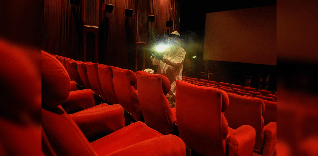A worker wearing a PPE kit sanitizes a movie theatre at DLF Promenade Mall in Vasant Kunj, New Delhi. Credit: PTI