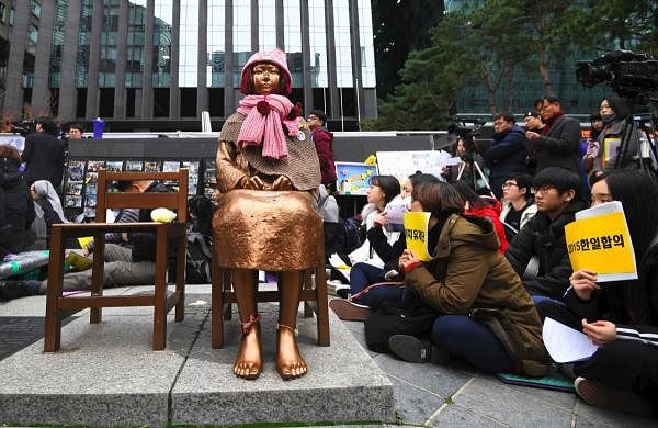 South Korean protesters sit near a statue of a teenage girl symbolizing former "comfort women". Credit: AFP Photo