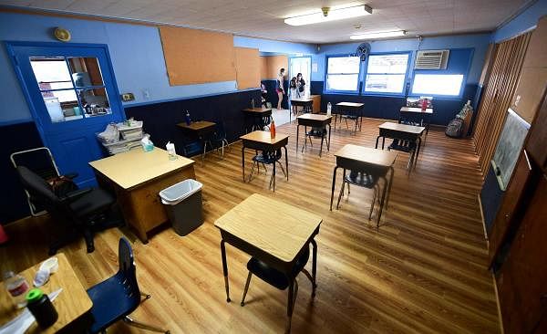 Children in an elementary school class wearing masks enter the classroom with desks spaced apart as per coronavirus guidelines. Credit: AFP