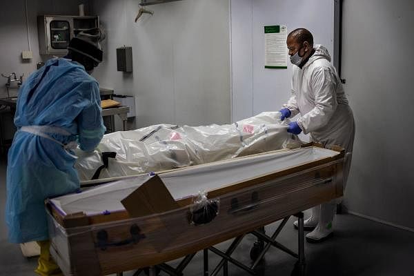 Undertakers move the remains of a Covid-19 coronavirus patient into a coffin. Representative Image. Credit: AFP