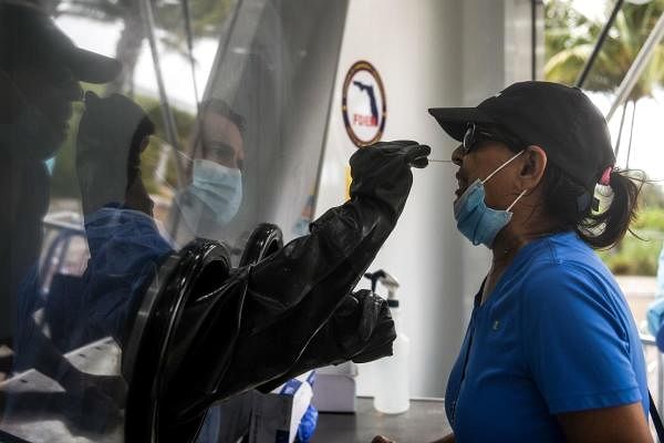 A nurse takes nose swabs through a glass pane at the Aardvark Mobile Health's Mobile Covid-19 Testing Truck. Credit: AFP