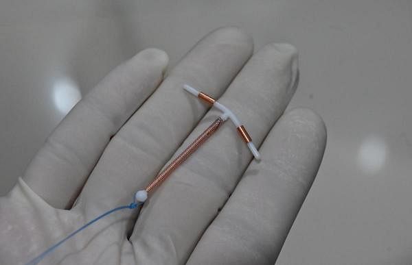 A doctor holding an IUD birth control device to put into a patient's womb at a clinic. Credit: AFP