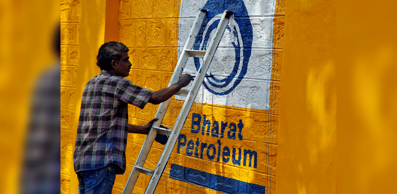 A man paints the logo of oil refiner Bharat Petroleum Corp on a wall on the outskirts of Kochi. Credits: Reuters Photo
