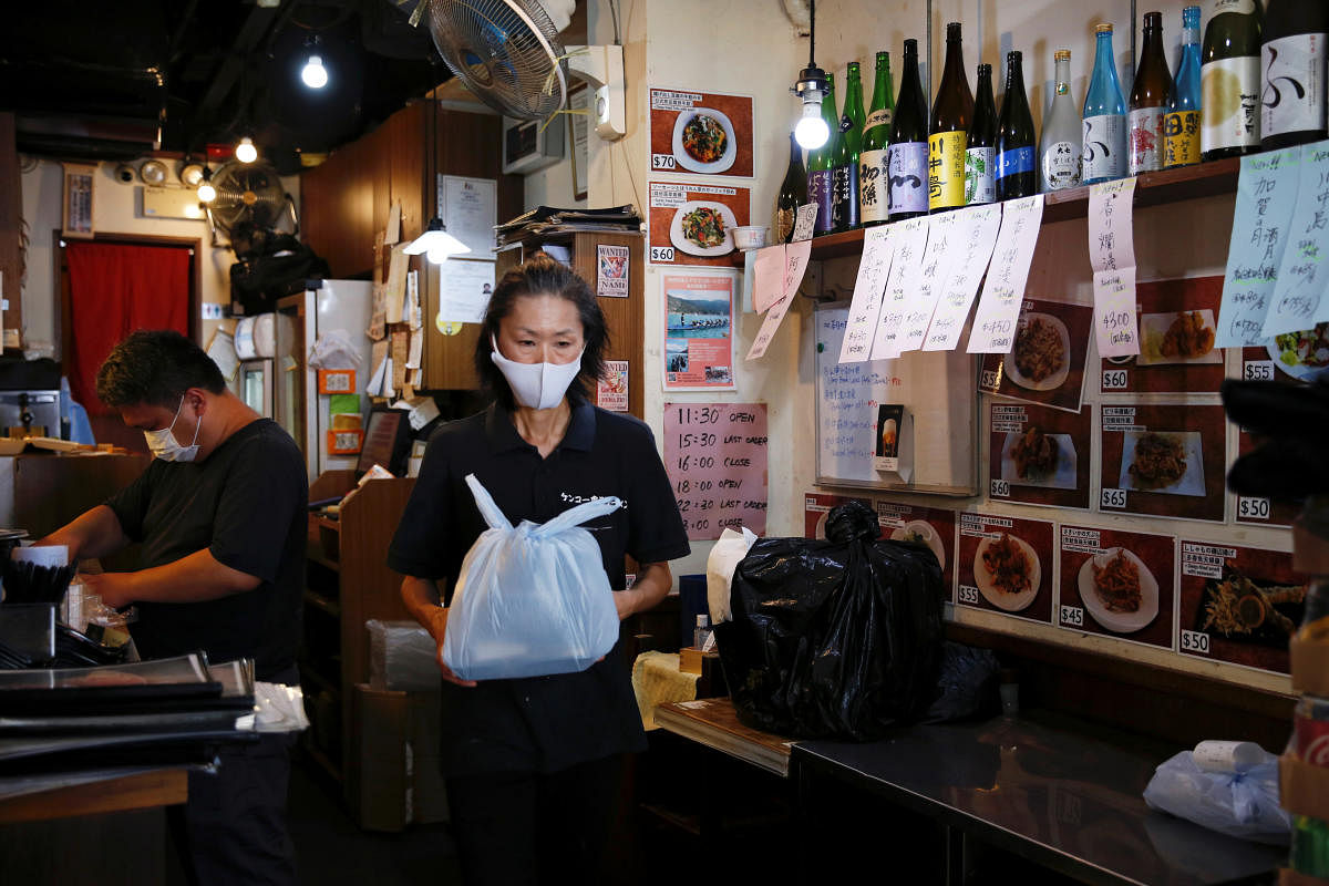 A worker holds a plastic bag containing a take-away lunch at a restaurant, after the government banned dine-in services, following the coronavirus disease. Credit: Reuters