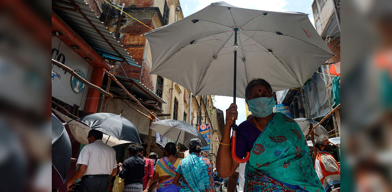People hold umbrellas distributed by volunteers to maintain social distancing as a preventive measure against the COVID-19 coronavirus, at a market in Chennai. Credit: AFP