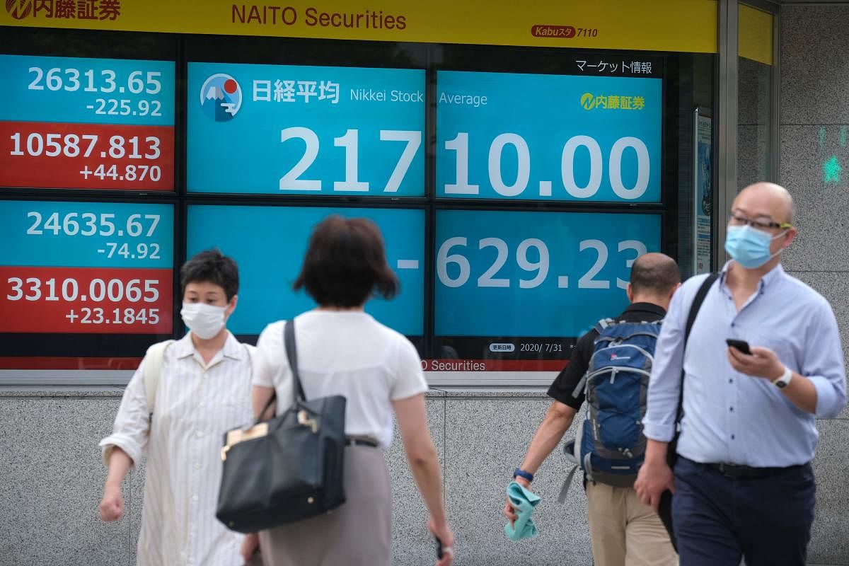 Pedestrians walk past an electronic quotation board displaying share prices from the Tokyo Stock Exchange in Tokyo on July 31, 2020.  Credit: AFP Photo