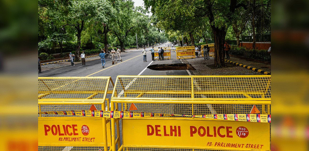 Police barricades put in place near a caved-in portion of the Ashok Road following rains in New Delhi. Credits: PTI Photo