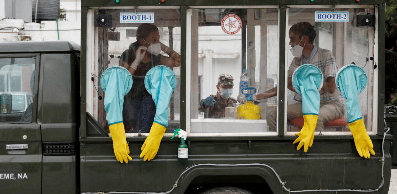 Health officials sit inside a mobile swab collection vehicle as they wait to test civil servants for the coronavirus disease in Kathmandu, Credit: Reuters