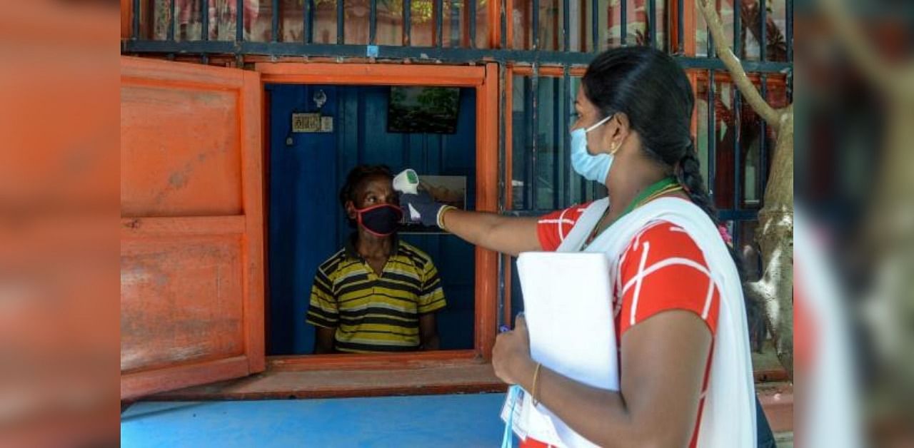 A health worker (R) checks the body temperature of a man at a containment zone implemented as a preventive measure against the Covid-19 coronavirus in Chennai on July 30, 2020. Credit: AFP Photo