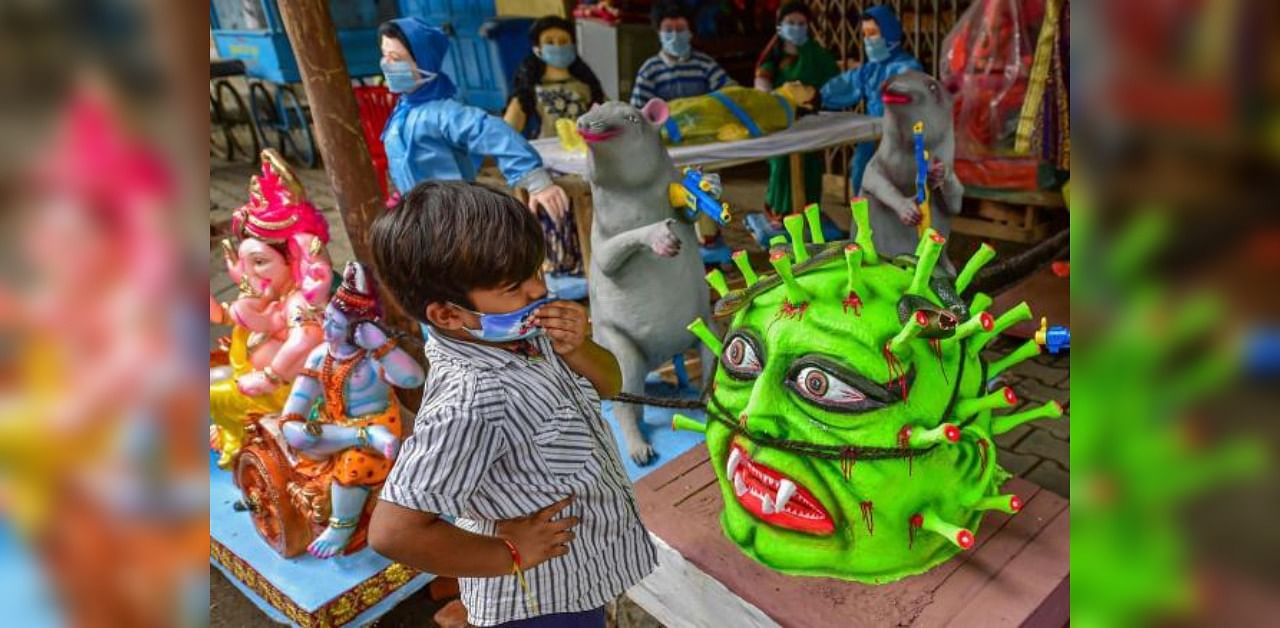 A boy stands near a coronavirus themed idol. Credit: PTI