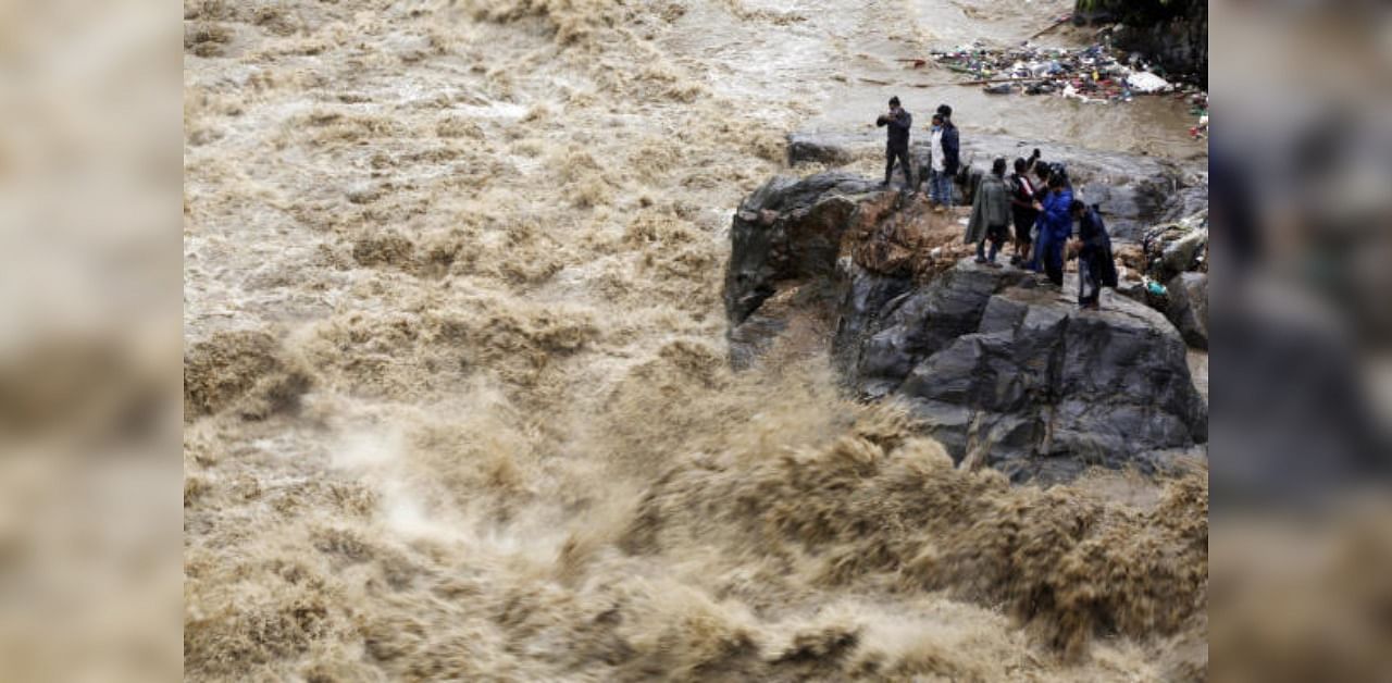 Nepalese people takes photos on the banks of flooded Bagmati river in Kathmandu, Nepal. Credit: AP