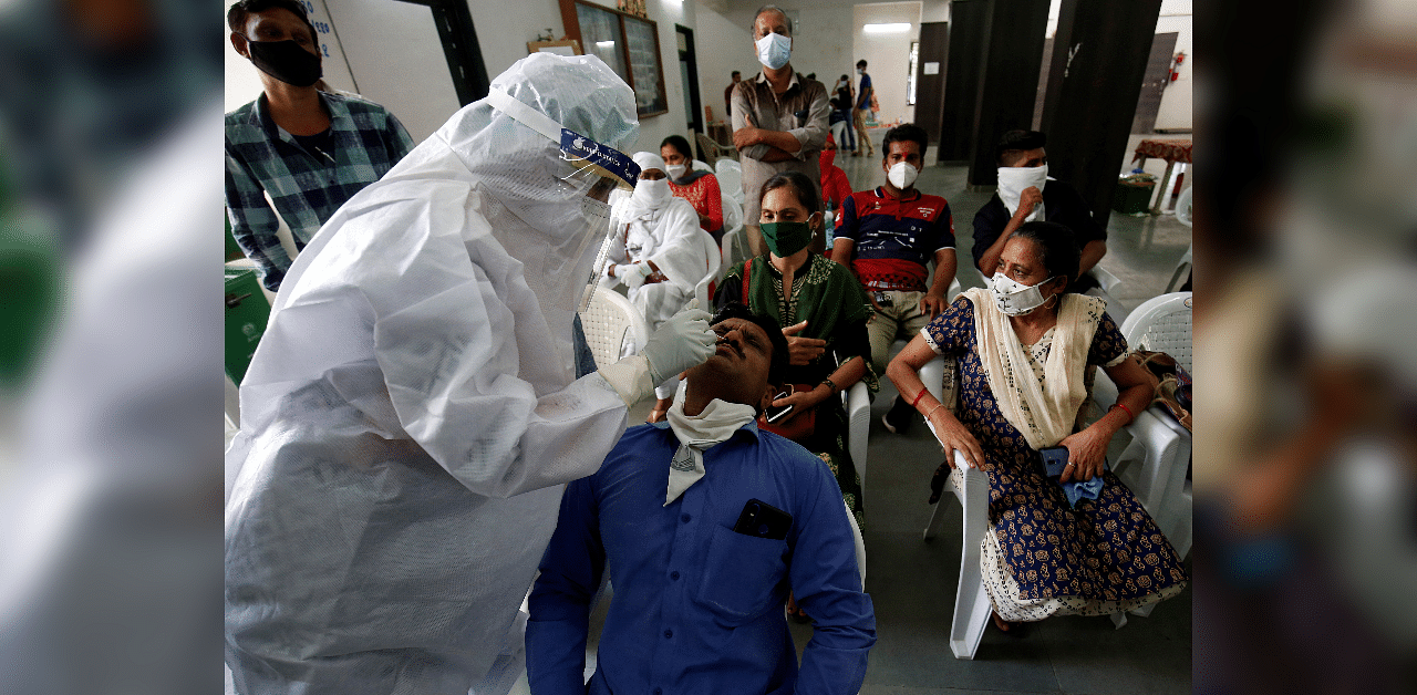 A healthcare worker wearing personal protective equipment (PPE) takes swab from a teacher of a municipal school for a rapid antigen test at a community center, amidst the coronavirus. Credits: Reuters Photo