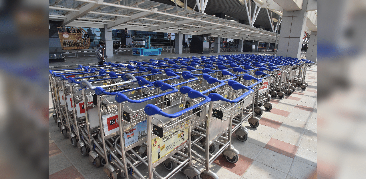 A security guard walks near luggage trolleys at KIAL during the nationalwide lockdown for Covid-19, in Bengaluru. Credit: DH Photo