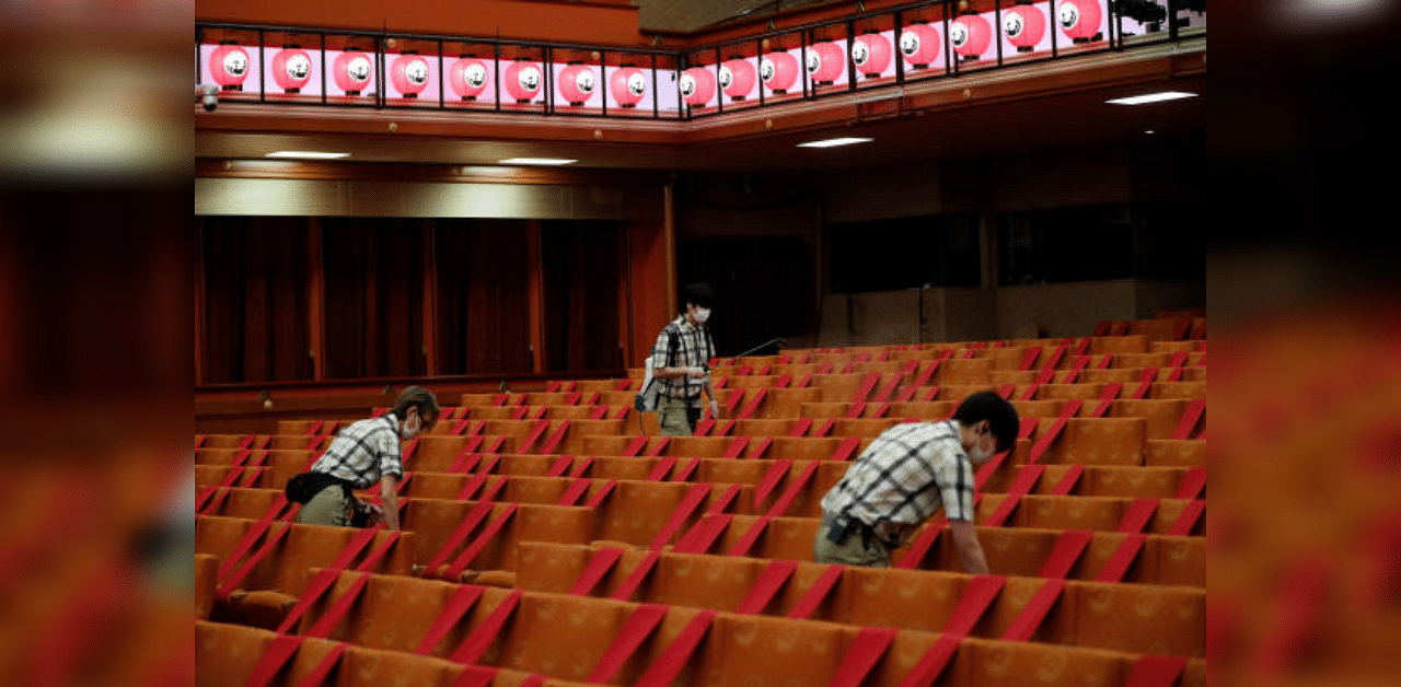 Workers wearing protective face masks disinfect seats at the Kabukiza Theatre. Credit: Reuters Photo