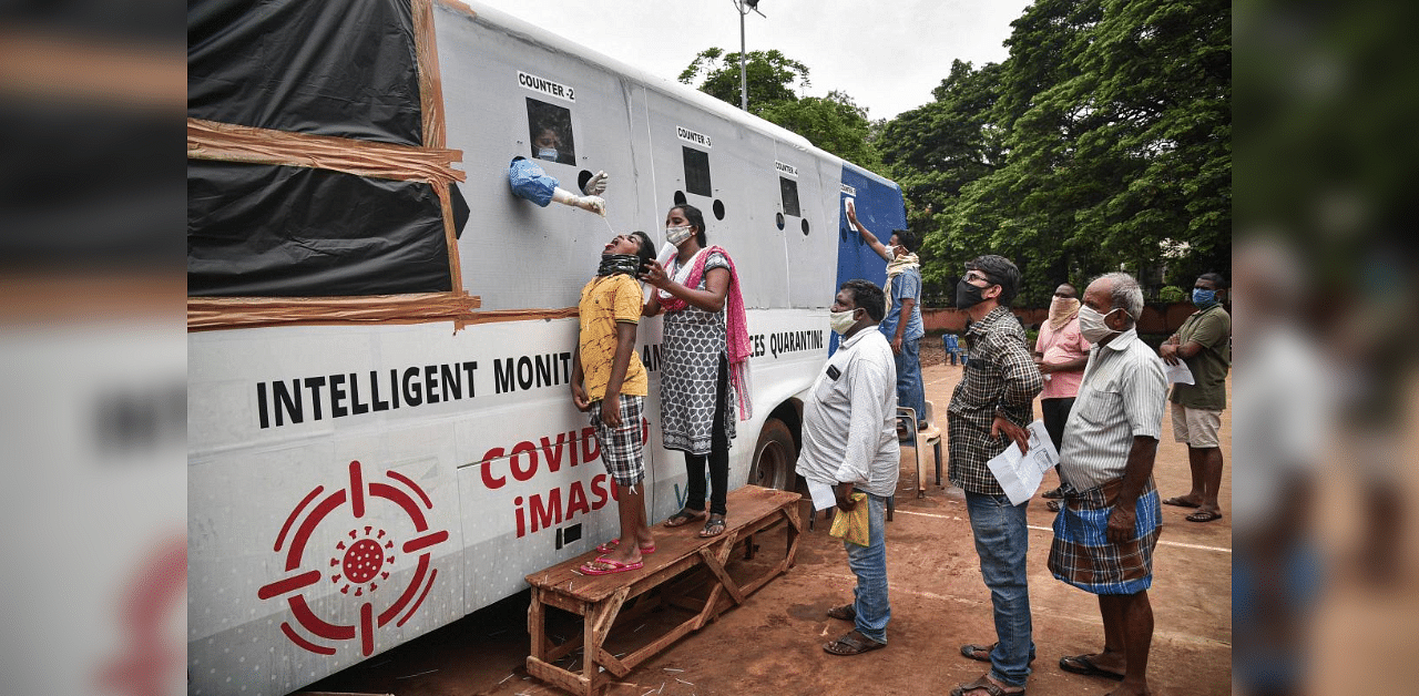 A medic collects samples for Covid-19 test from a mobile swab collection vehicle at Indira Gandhi Municipal Corporation Stadium, in Vijayawada. Credit: PTI Photo