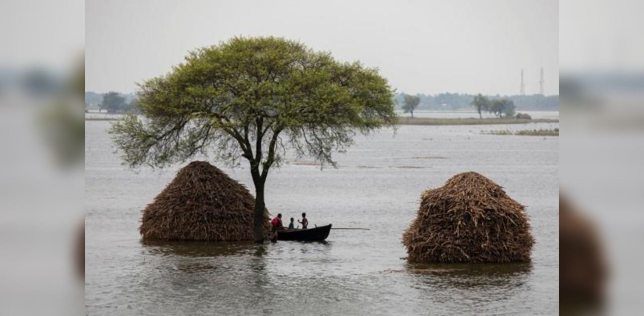 A woman with two children rows a small boat in a flooded field in Bhagalpur district in the eastern state of Bihar, India. Credit: Reuters Photo