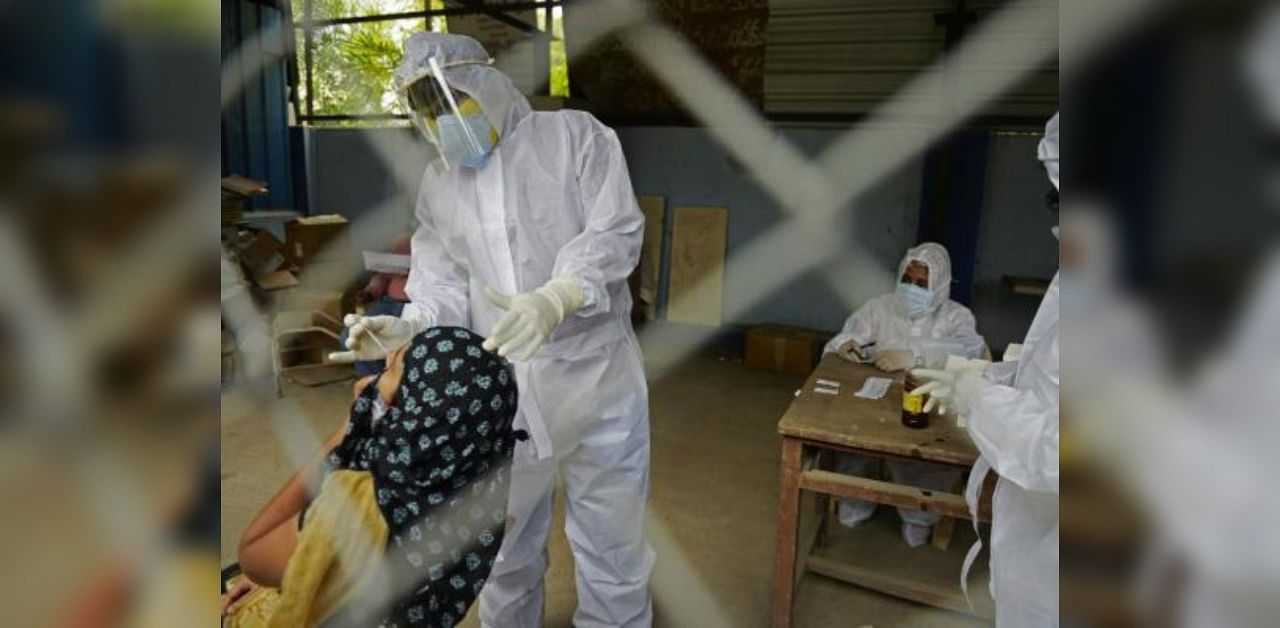 A health worker wearing Personal Protective Equipment (PPE) gear collects a swab sample of a resident at a free testing centre for the COVID-19. Credit: AFP