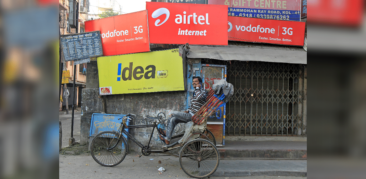  A rickshaw puller speaks on his mobile phone as he waits for customers in front of advertisement billboards belonging to telecom companies. Credits: Reuters Photo