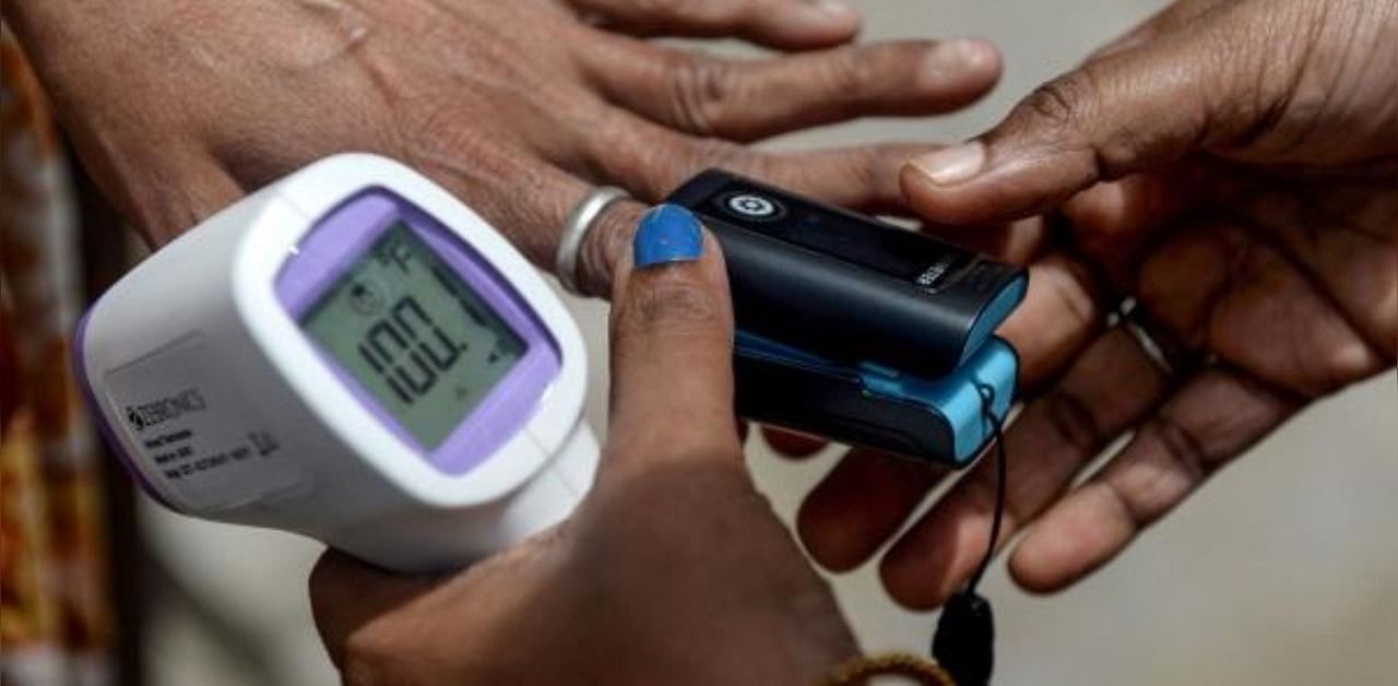 A health worker checks the oxygen saturation level of a woman using a pulse oximeter at a containment zone implemented as a preventive measure against the coronavirus. Credit: AFP