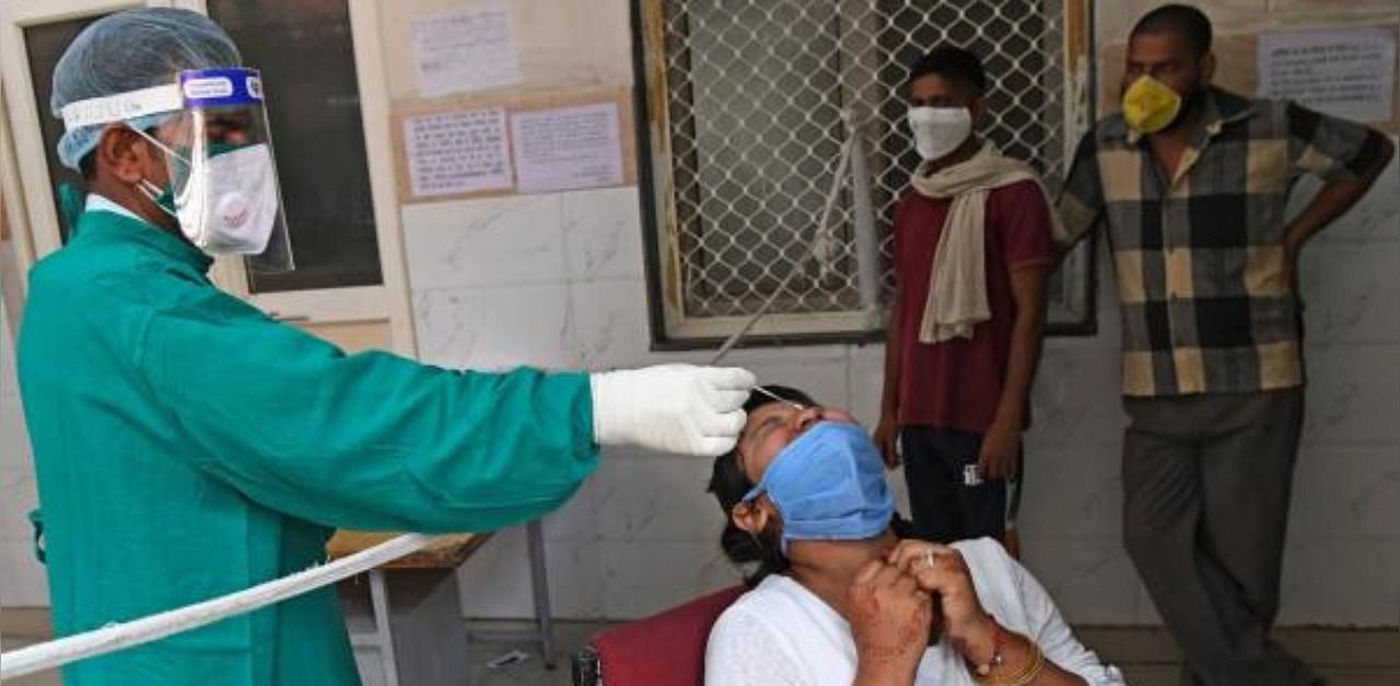 A medical staff collects a nasal swab of a man with a Rapid Antigen Test (RAT) kit for the coronavirus, at a testing centre in Ghaziabad. Credit: AFP