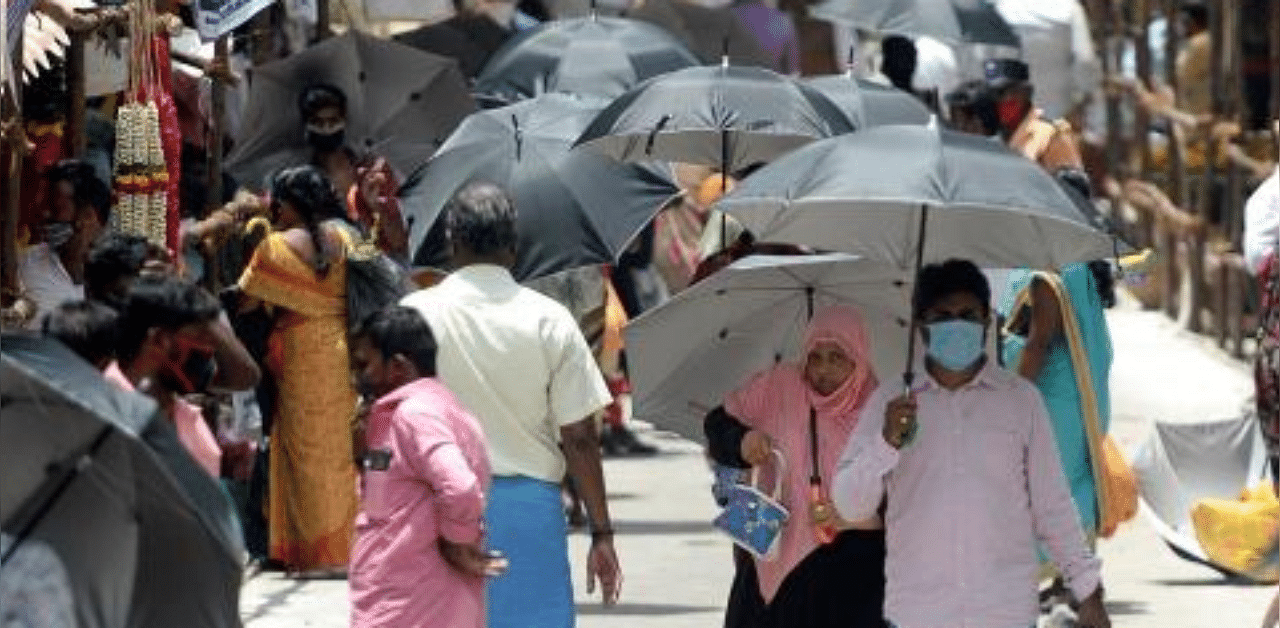 People hold umbrellas distributed by volunteers to maintain social distancing as a preventive measure against the coronavirus, in a market in Chennai. Credit: AFP Photo