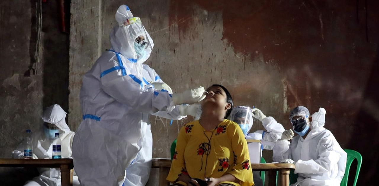 A healthcare worker wearing personal protective equipment (PPE) takes swab from a woman to test for the coronavirus disease (COVID-19) in Kolkata. Credit: Reuters Photo