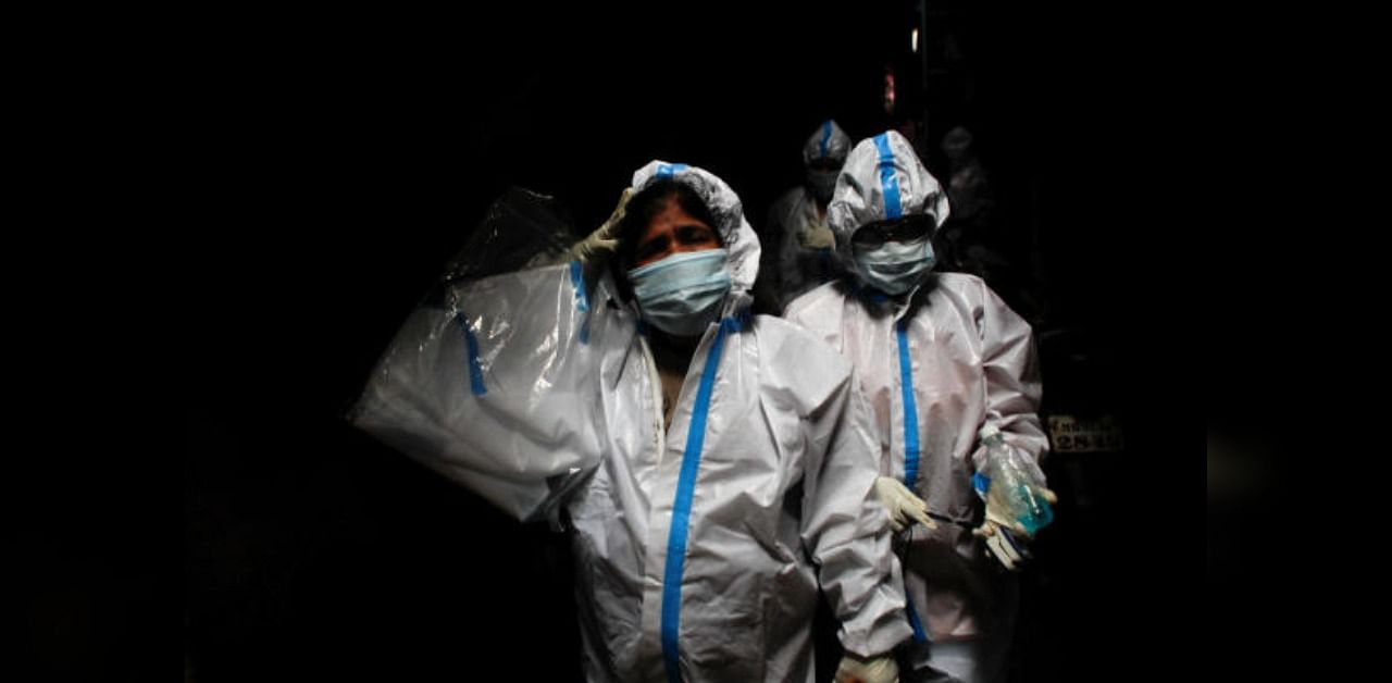 A health worker in personal protective equipment reacts as she and the rest of the team walk through an alley during a check up campaign for the coronavirus disease (COVID-19) at a slum area in Mumbai. Credit: Reuters
