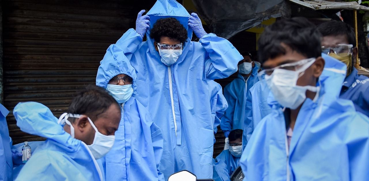 Health workers wear PPE kits before conducting medical check-up. Credit: PTI Photo