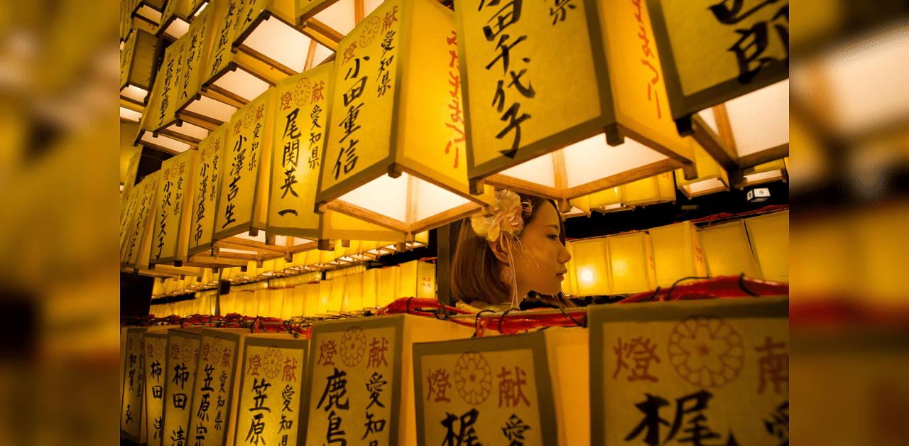 A woman stands between lanterns during the annual four-day Mitama Festival at the Yasukuni Shrine, where more than 2.4 million war dead are enshrined, in Tokyo, Japan. Credit: Reuters