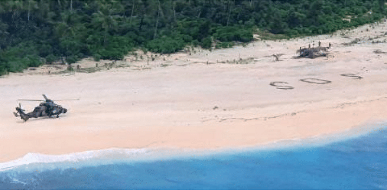 Australian Army ARH Tiger helicopter landing near the letters "SOS" (C) on a beach on Pikelot Island where three men were found in good condition after being missing for three days. Credit: AFP Photo