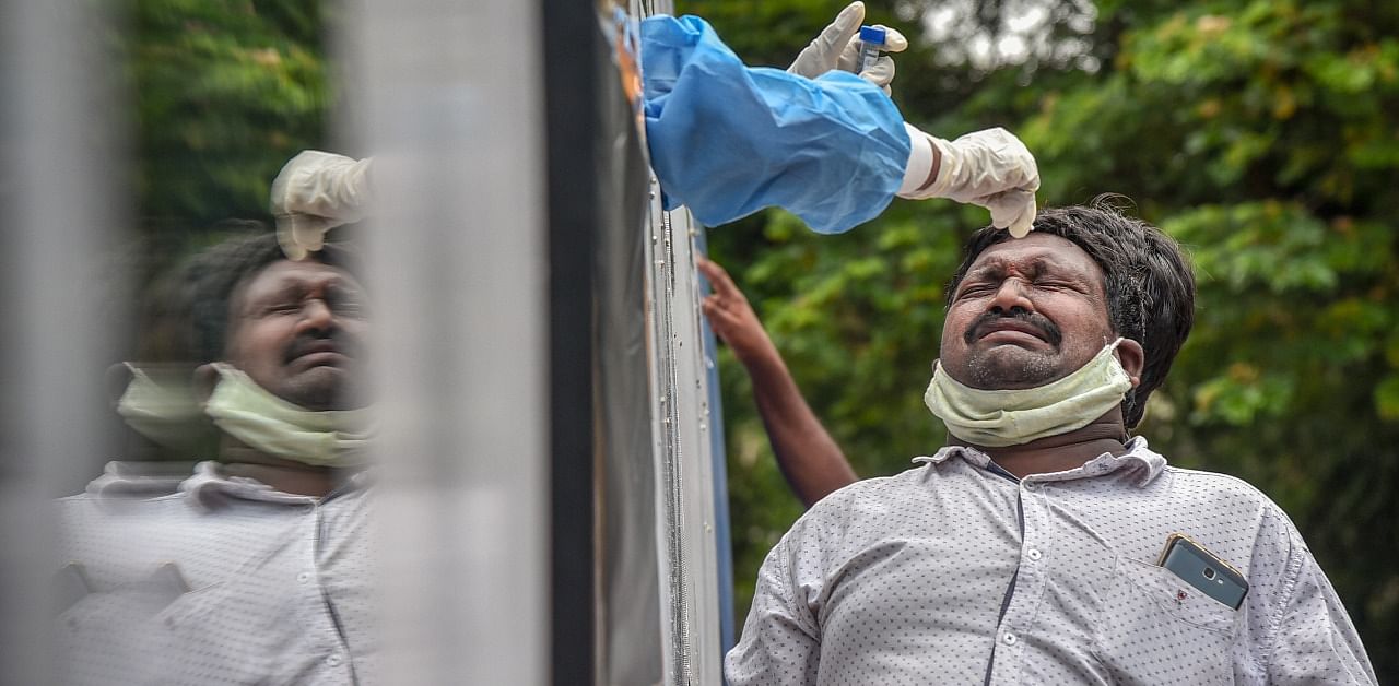 A man reacts while a medic collects a nasal sample for the Covid-19 test from a mobile swab collection vehicle. Credit: PTI Photo