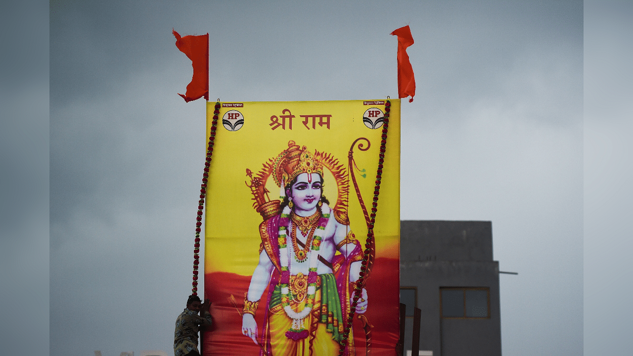A worker erects a large poster of Hindu Lord Ram on the roof of a service station. Credits: AFP Photo