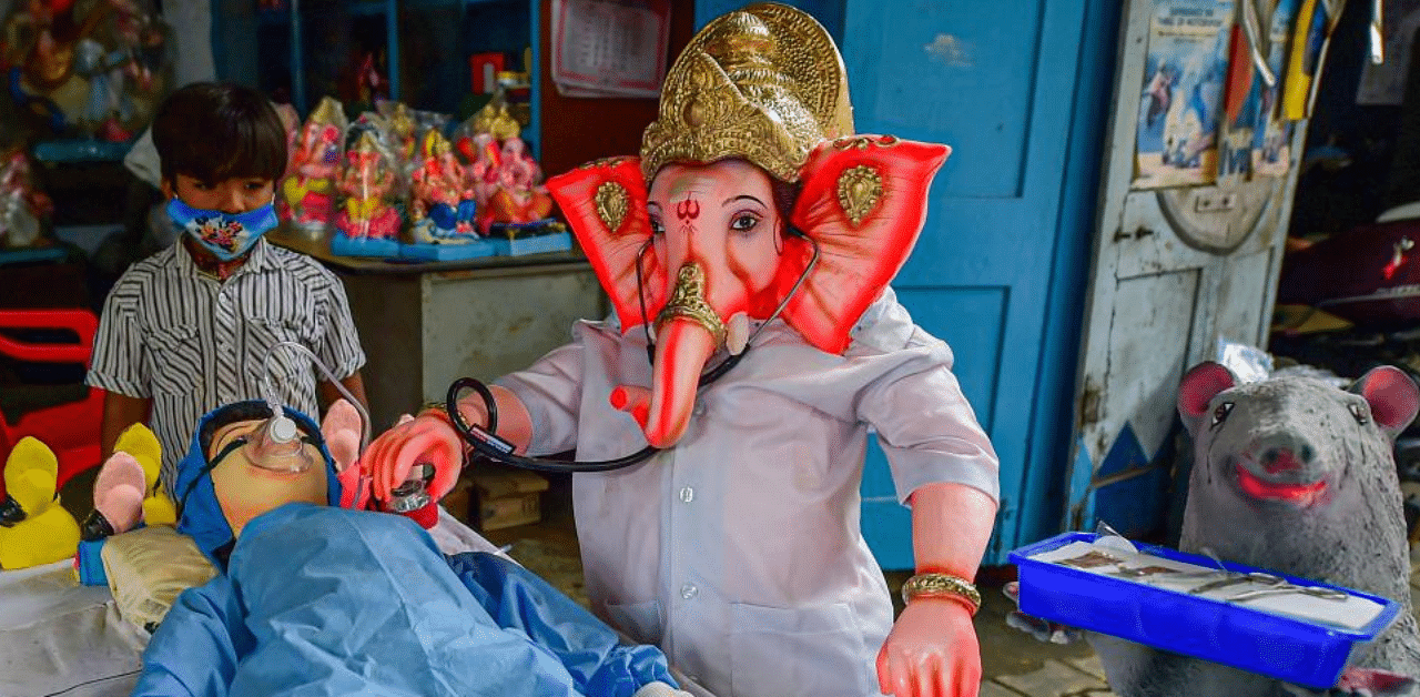 A boy stands near the Covid-19 warrior themed idols for Puja festivities at a workshop, in Bengaluru, Saturday, Aug. 1, 2020. Credit: PTI Photo
