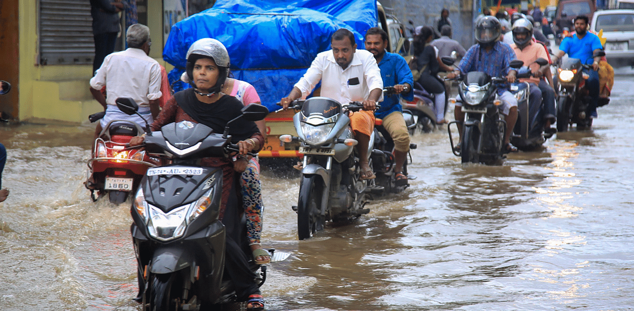 Commuters ply across a waterlogged street following rainfall. Credits: PTI Photo