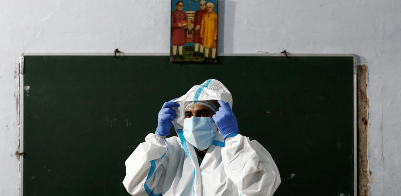 A health worker adjusts his personal protective equipment (PPE) before collecting samples at a school which was turned into a centre to conduct tests for the coronavirus disease, amidst the spread of the disease, in New Delhi, India, August 6, 2020. Credit: Reuters Photo