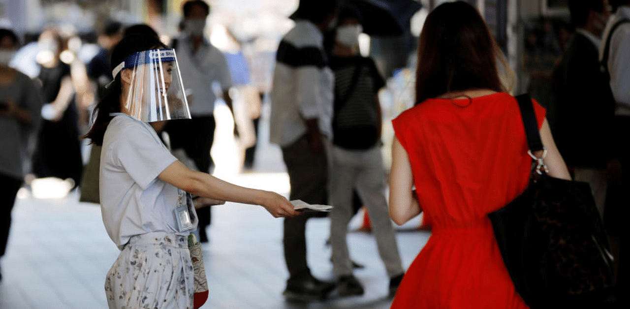 A saleswoman wearing a face shield distributes leaflets on the street amid the coronavirus disease in Japan. Credit: Reuters