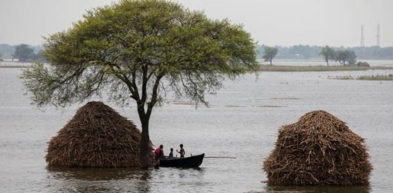 A woman with two children rows a small boat in a flooded field in Bhagalpur district in the eastern state of Bihar, India. Credit: Reuters Photo