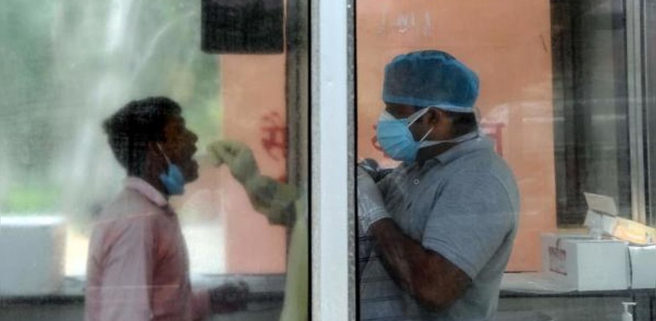 a medical staff (R) takes a sample from a man for a coronavirus test at Lala Lajpat Rai Memorial (LLRM) hospital in Meerut in Uttar Pradesh state. Credit: AFP