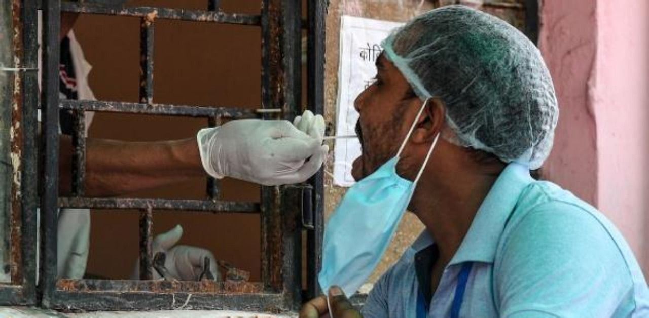 A medical staff (L) takes a sample from a man for a coronavirus test at Pyare Lal Sharma district hospital in Meerut in Uttar Pradesh state. Credit: AFP