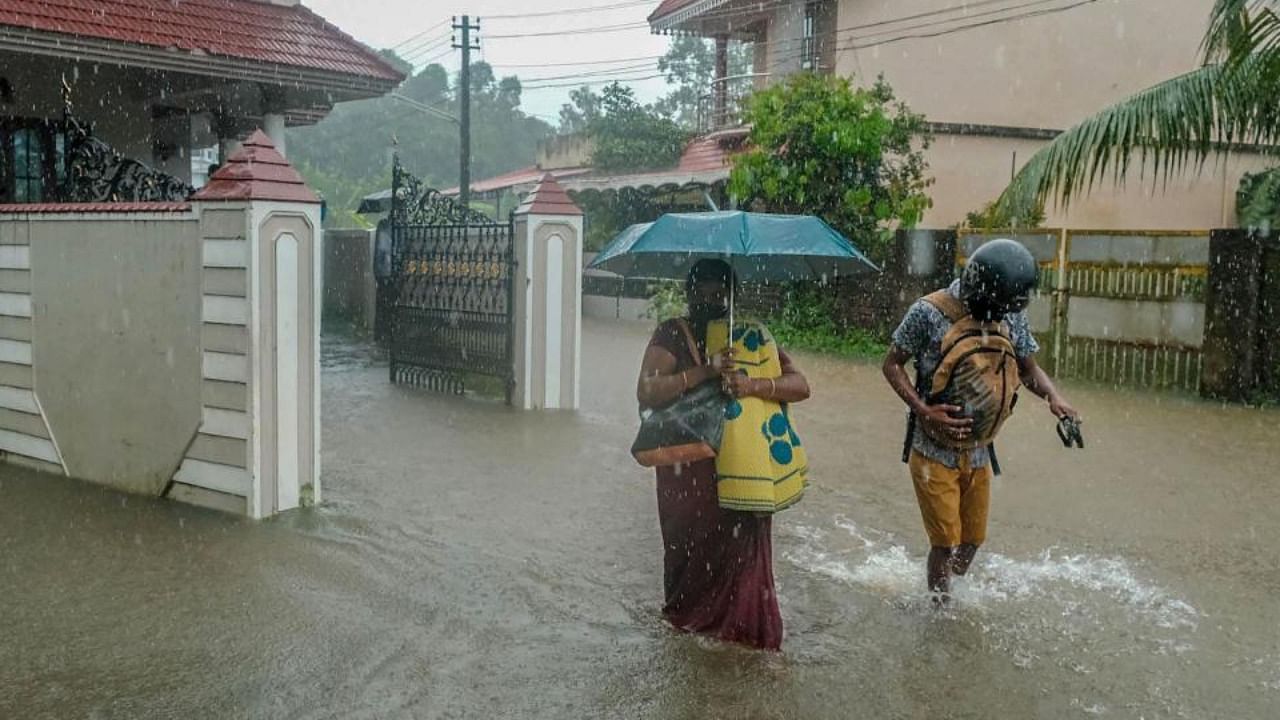 Locals wade through a flood affected area during heavy rainfall, in Kochi. Credit: PTI